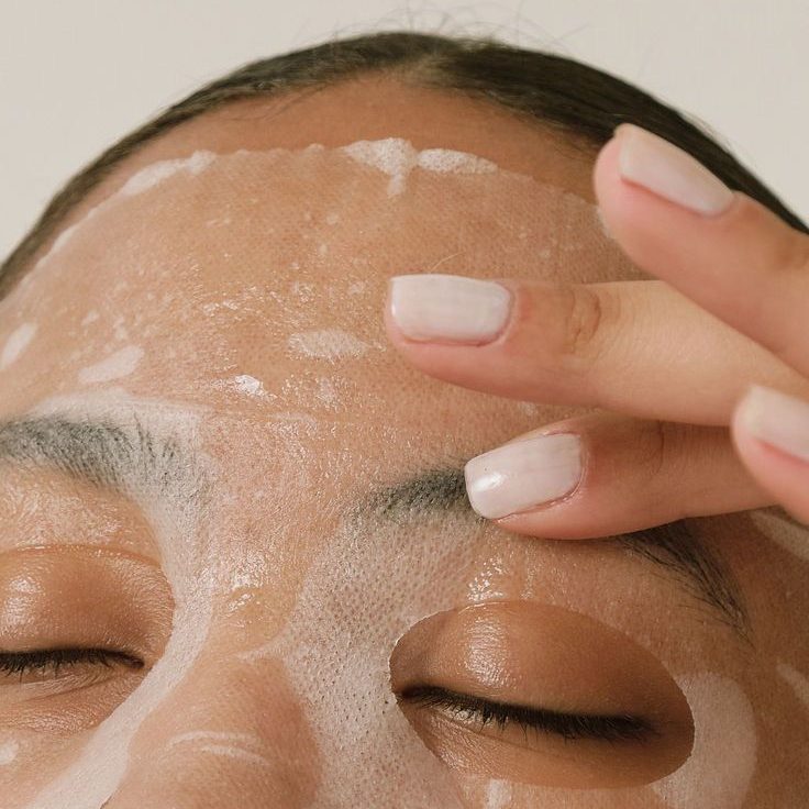 Femme appliquant un masque en feuille.